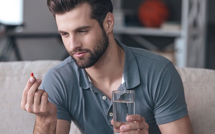 човек пије таблету за повећање главе пениса